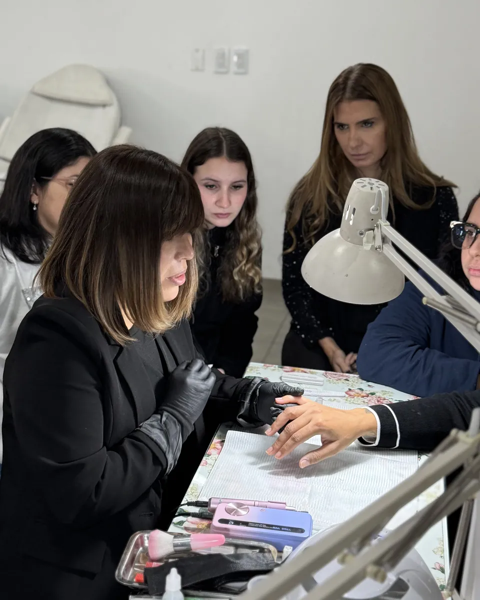 Varias alumnas alrededor de una mesa miran cómo una compañera trabaja sobre una mano.