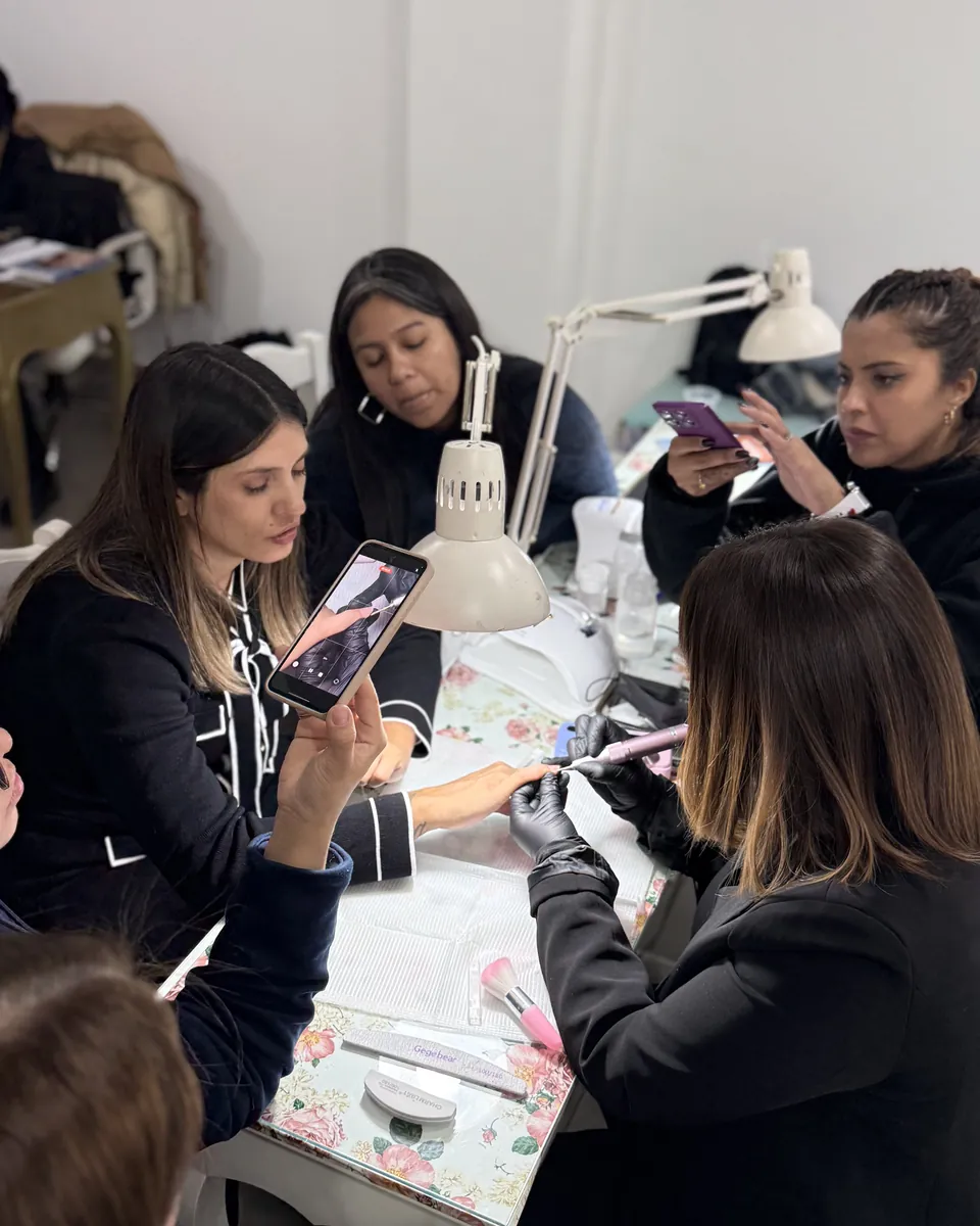 Un grupo de alumnas trabajando en la misma mesa: una registra el trabajo con el celular y otra sigue puliendo.