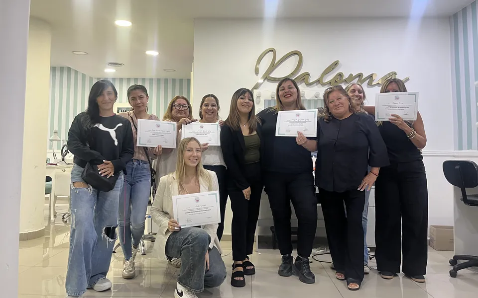 Un grupo grande de alumnas con sus certificados en el salón de la escuela, con una de ellas agachada adelante.